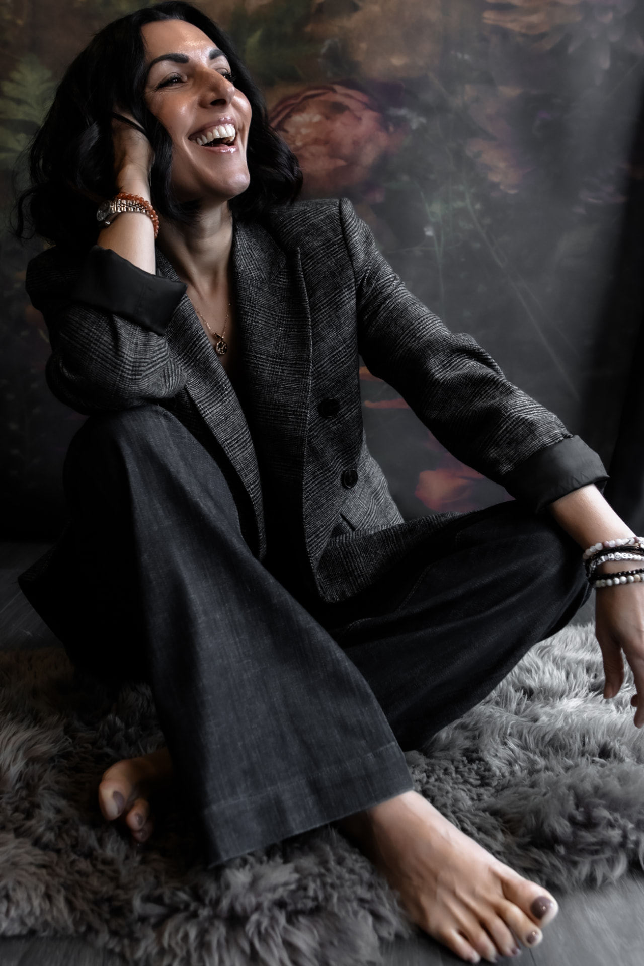 Naomi Buff sitting on a sheepskin rug, laughing